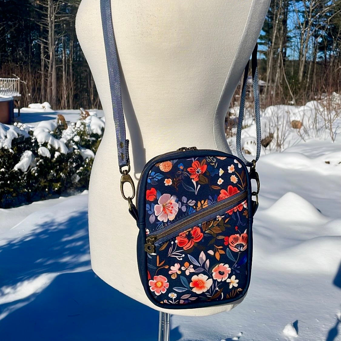 Sac bandoulière en liège bleu marin au devant en canevas à motif de fleurs.