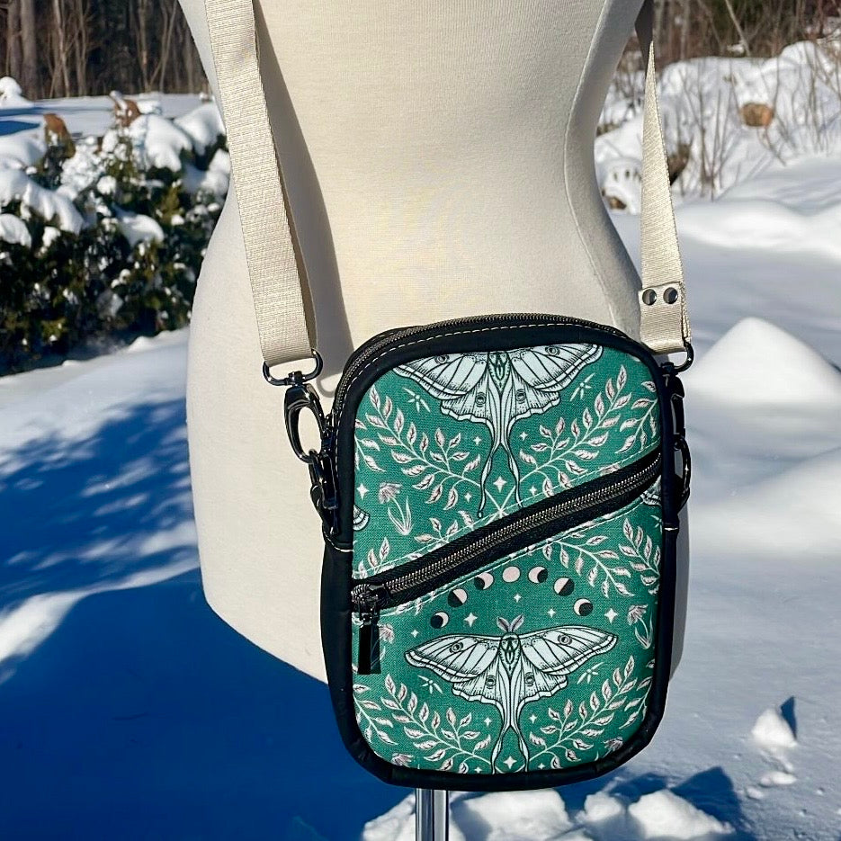 Sac bandoulière en liège noir au devant en canevas vert à motif de papillons noirs et beiges