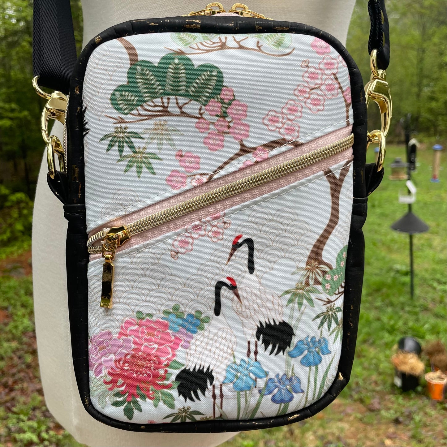Sac bandoulière en liège noir et doré au devant en canevas vert à motif de fleurs et de grues de style asiatique.