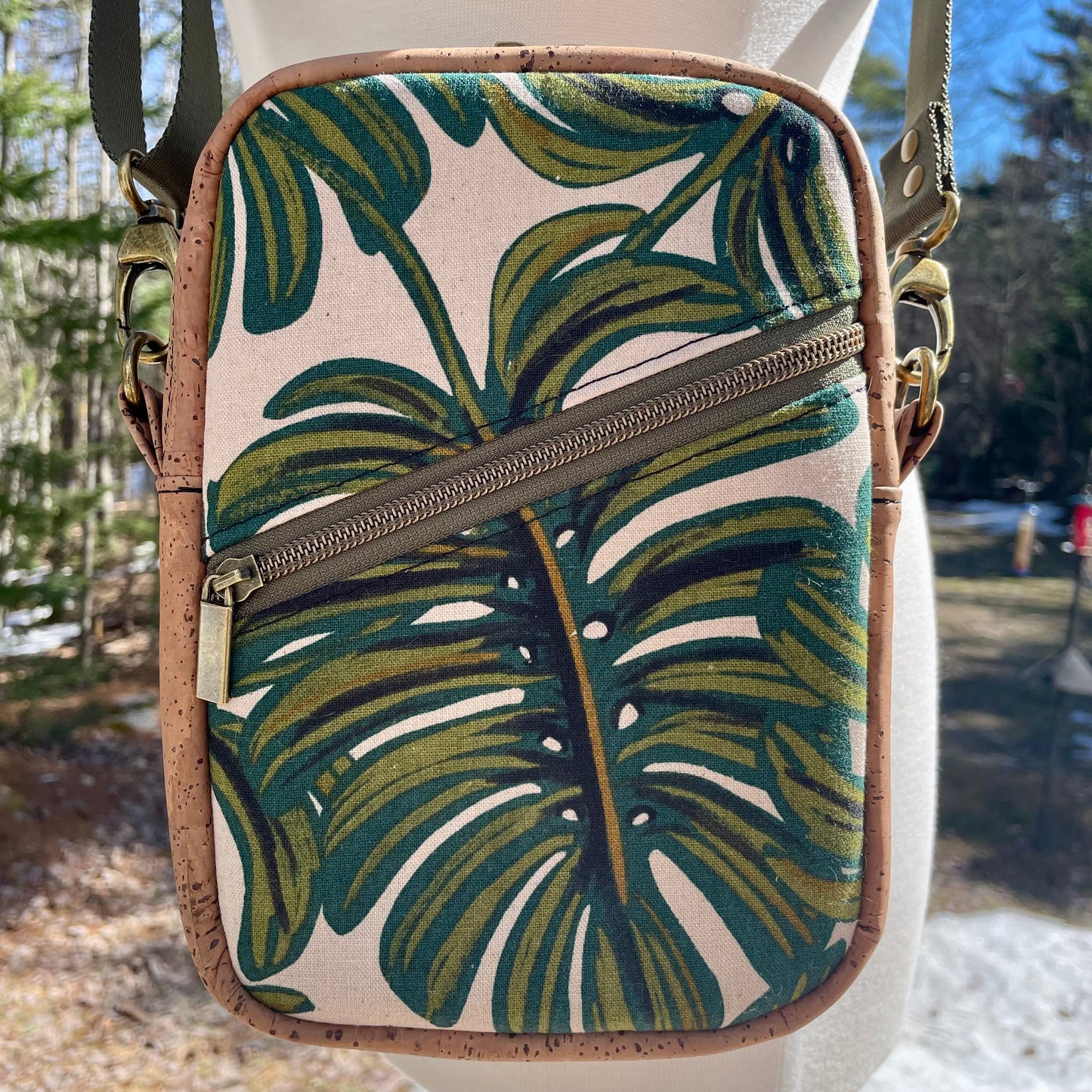 Sac bandoulière en liège brun pâle au devant en canevas à motif de feuille.