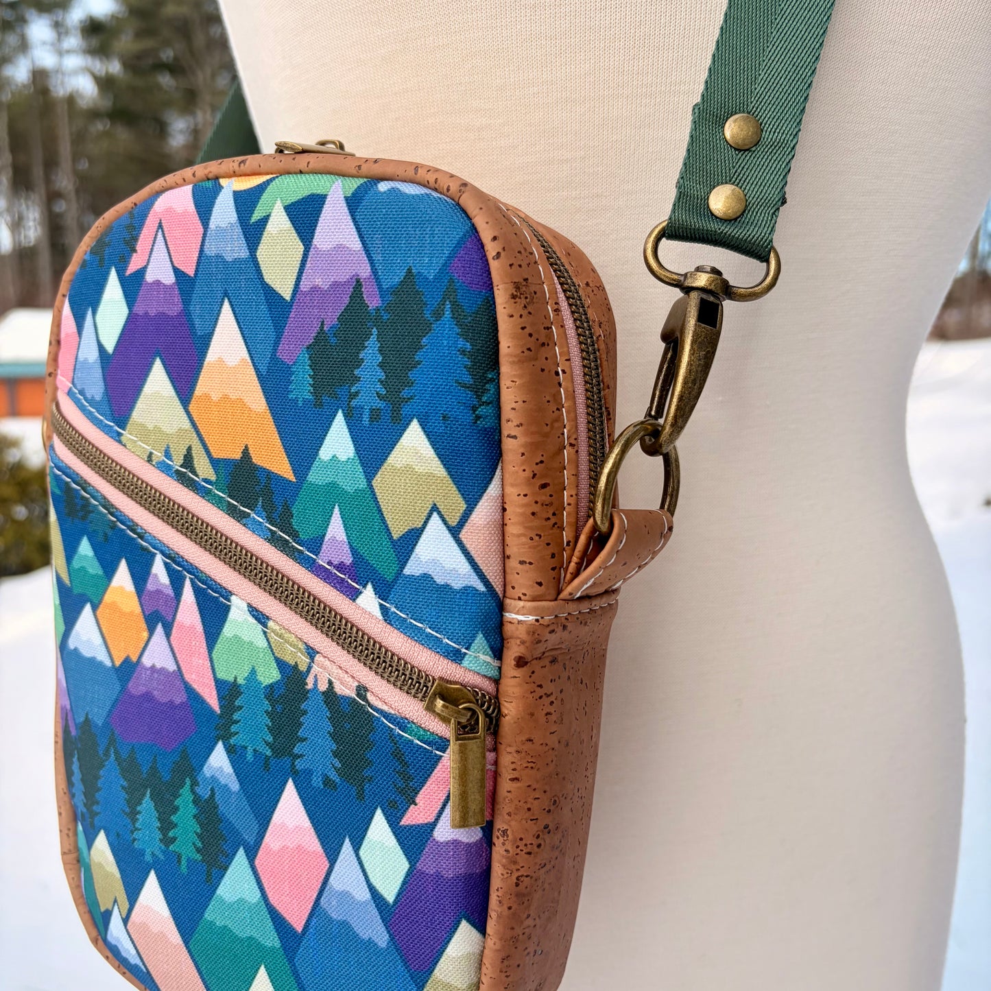 Sac bandoulière en liège brun pâle au devant en canevas à motif montagnes colorées.