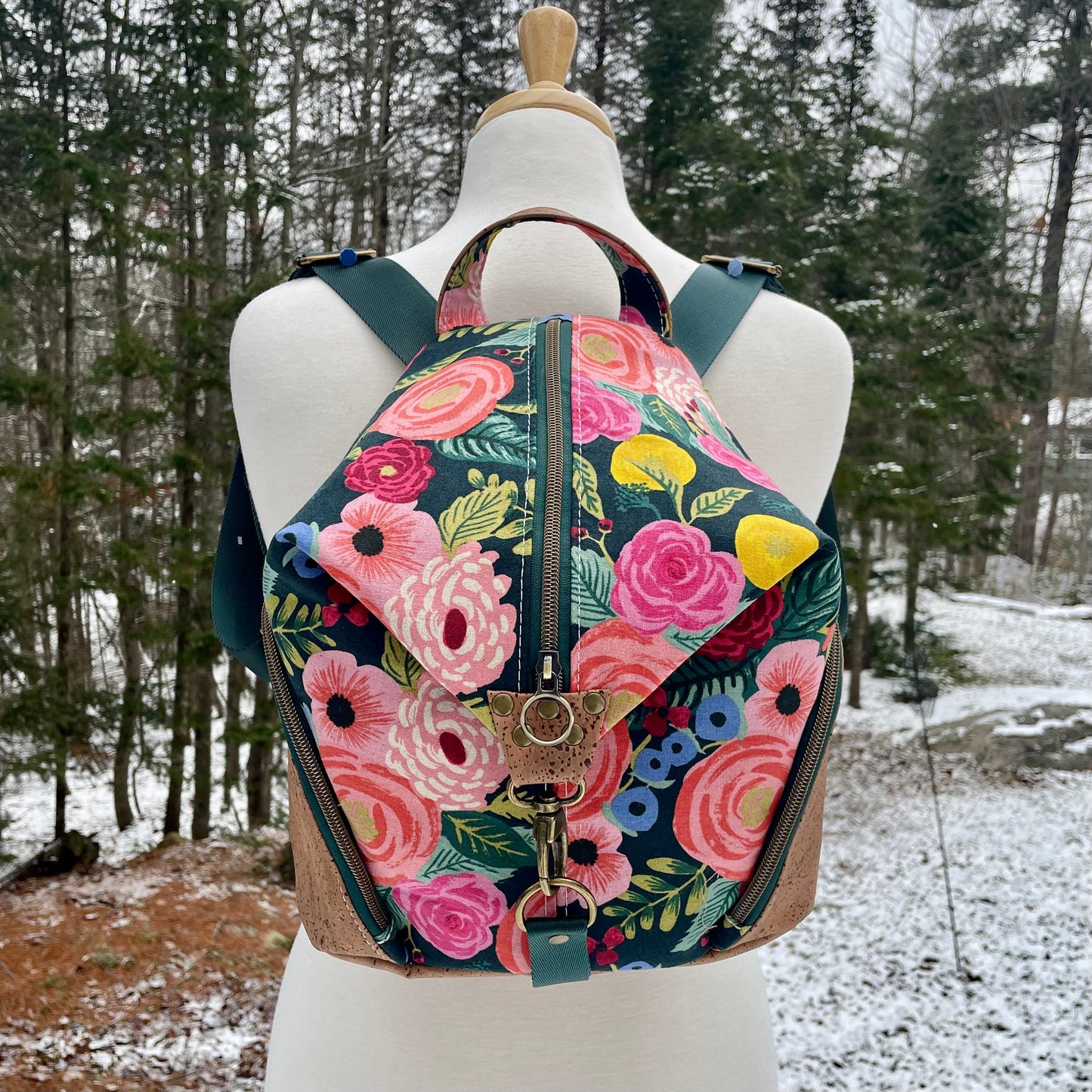 Sac à dos en canvas vert foncé à motifs de fleurs colorées et au liège brun pâle.