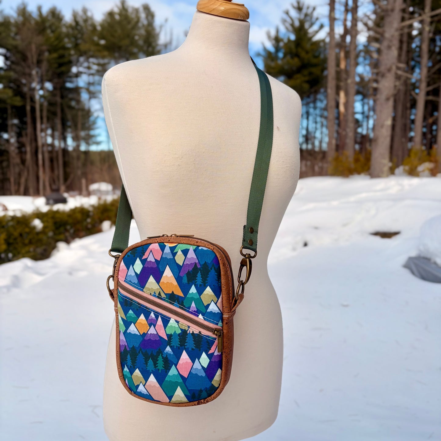 Sac bandoulière en liège brun pâle au devant en canevas à motif montagnes colorées.