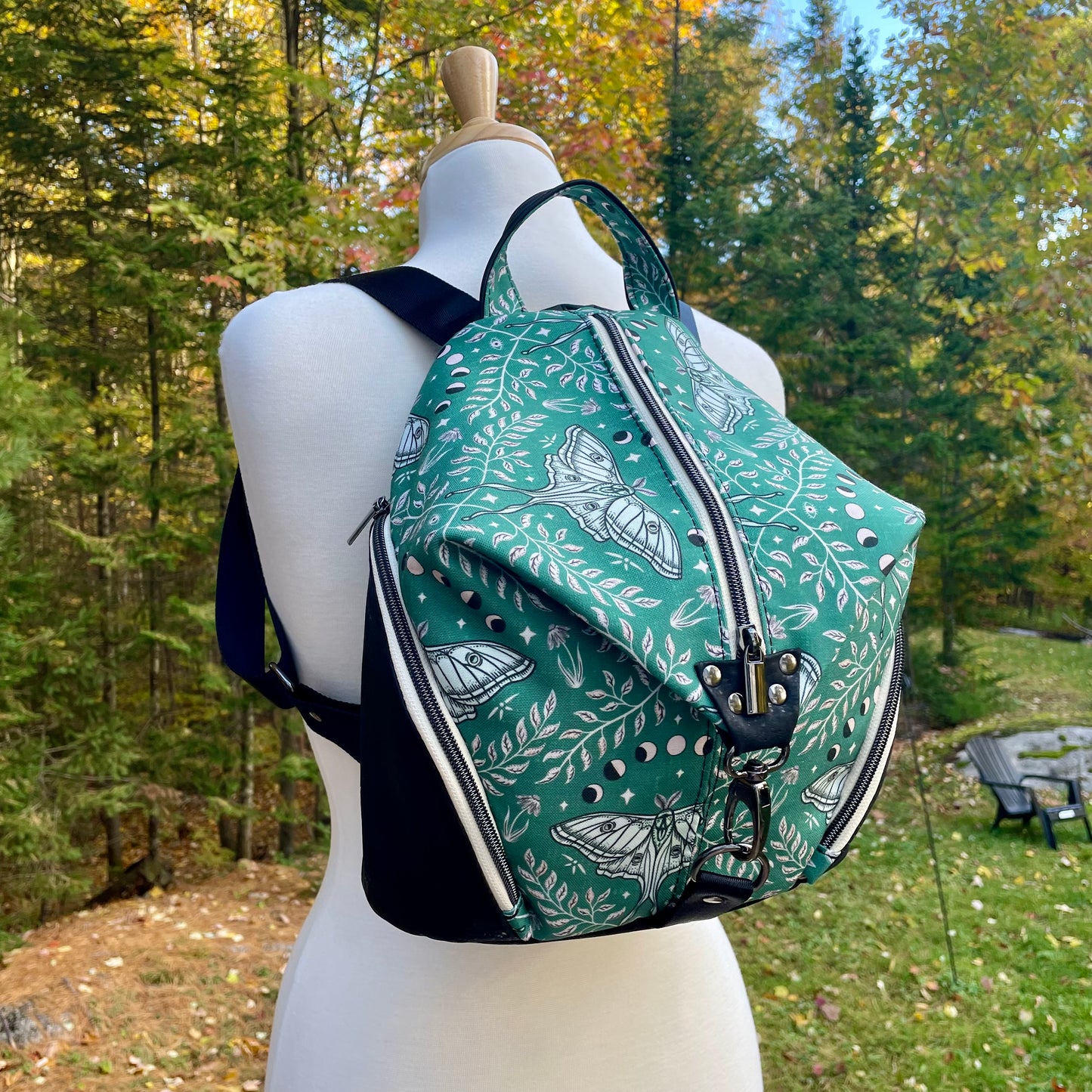 Sac à dos en canvas vert à motifs de papillons crèmes et au liège noir.