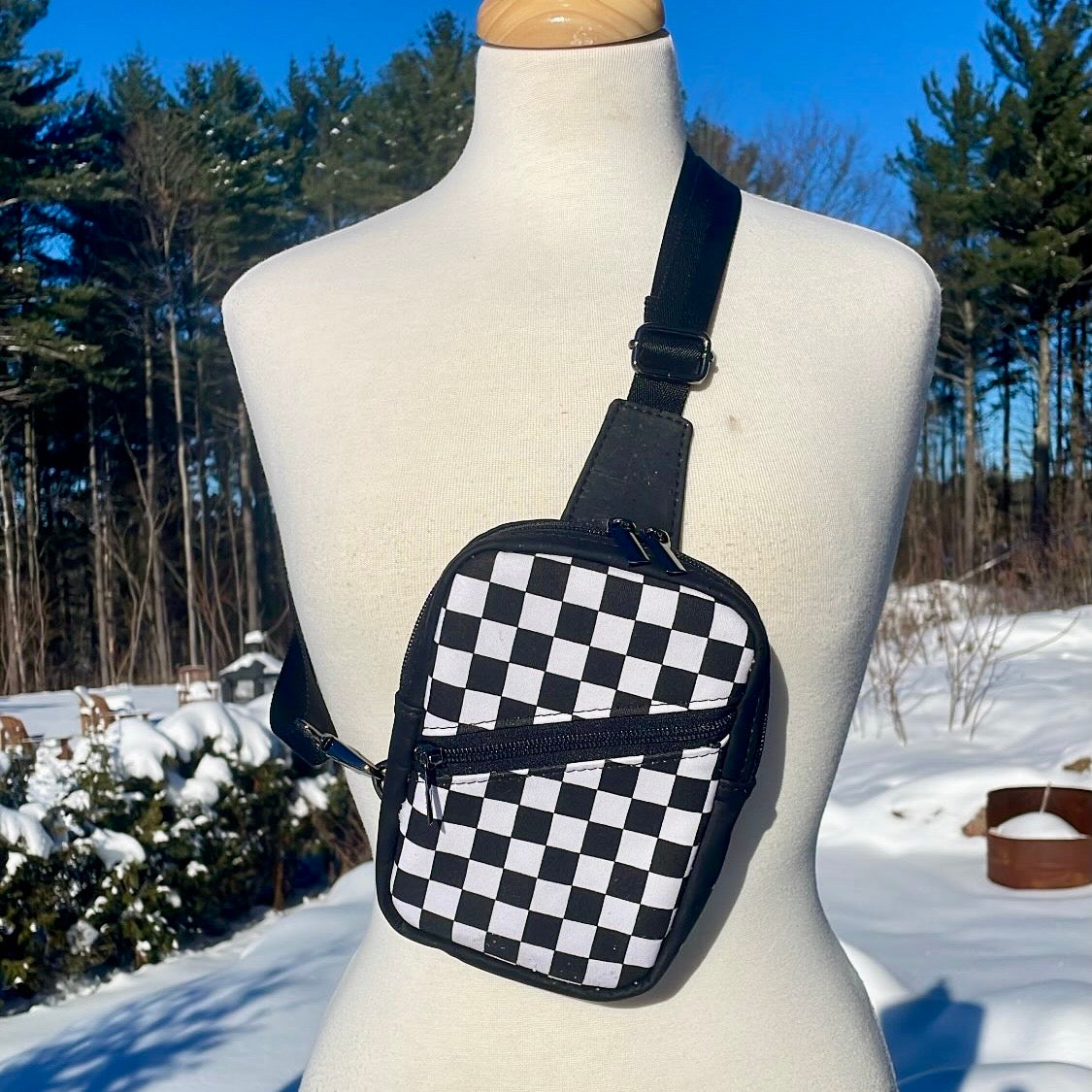 Sac de corps en liège noir au devant en canevas à motifs de damier noir et blanc.