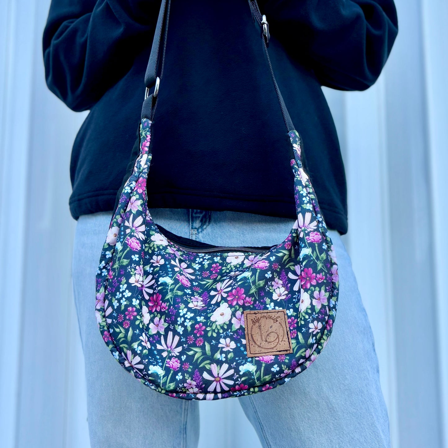 The Charlevoix - Black canvas half-moon bag with floral pattern and black.
