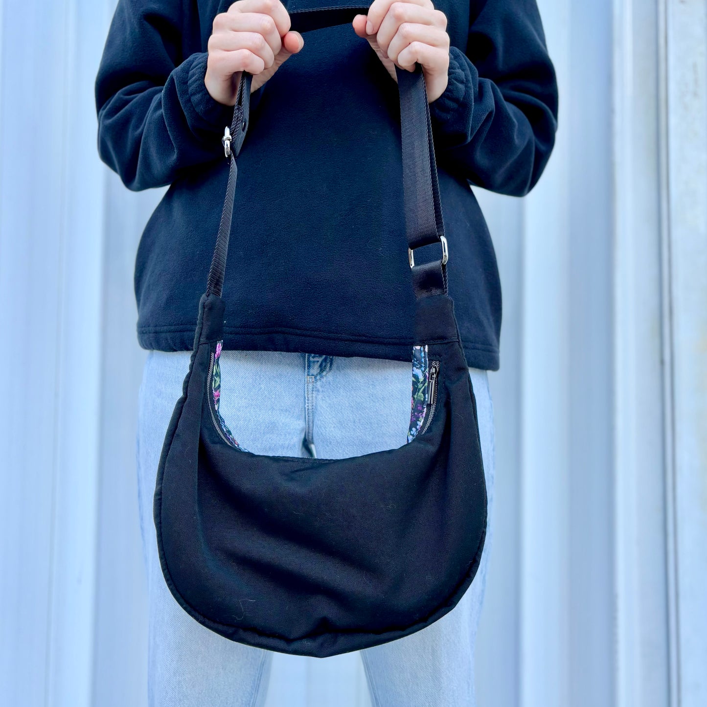 The Charlevoix - Black canvas half-moon bag with floral pattern and black.