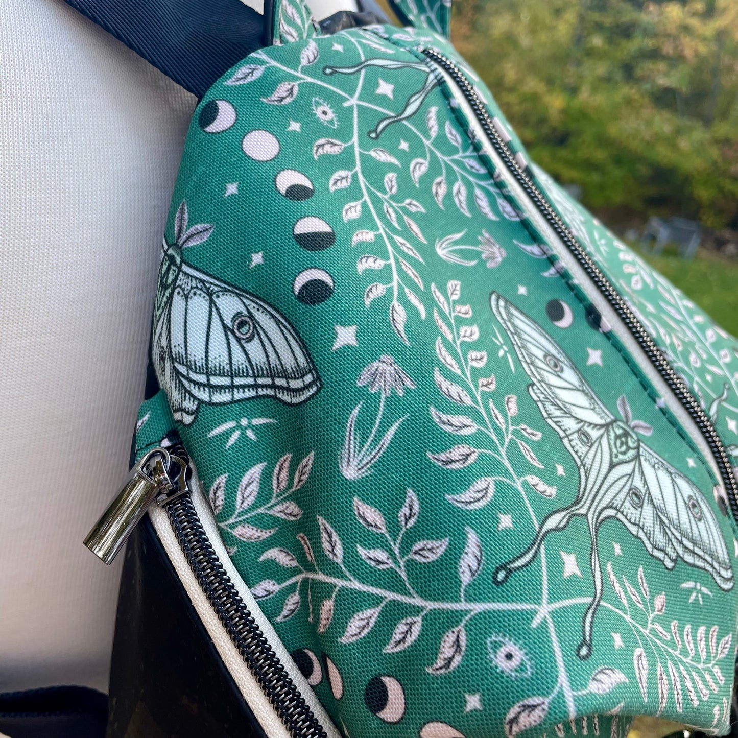 Sac à dos en canvas vert à motifs de papillons crèmes et au liège noir.