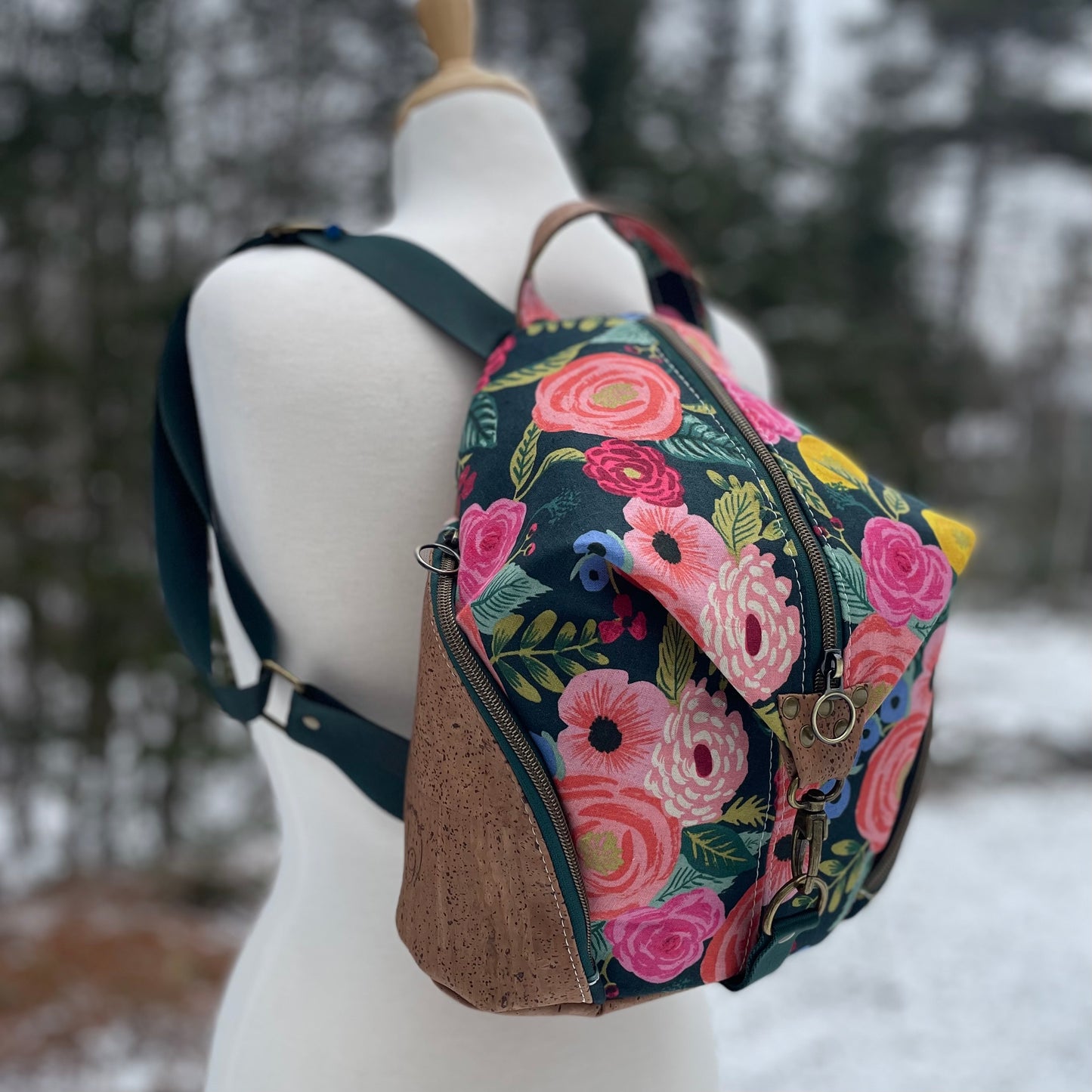 Sac à dos en canvas vert foncé à motifs de fleurs colorées et au liège brun pâle.