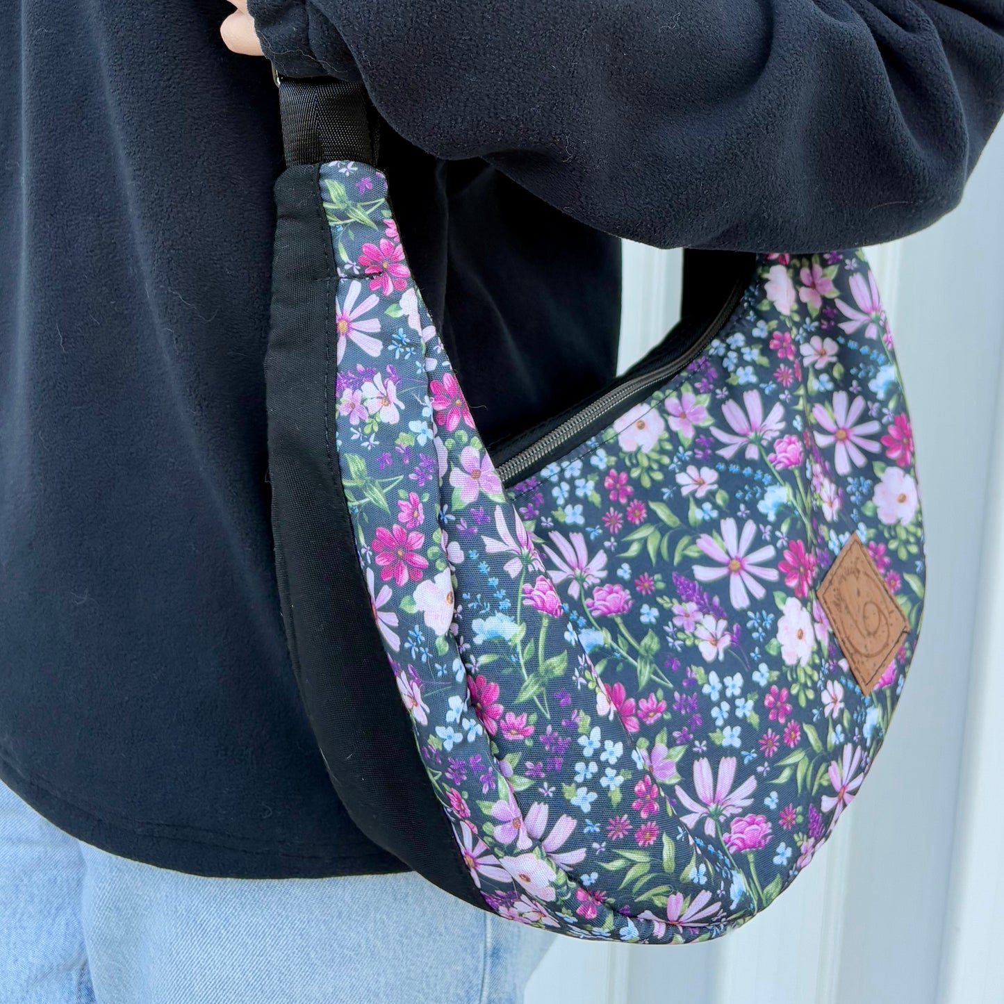 The Charlevoix - Black canvas half-moon bag with floral pattern and black.