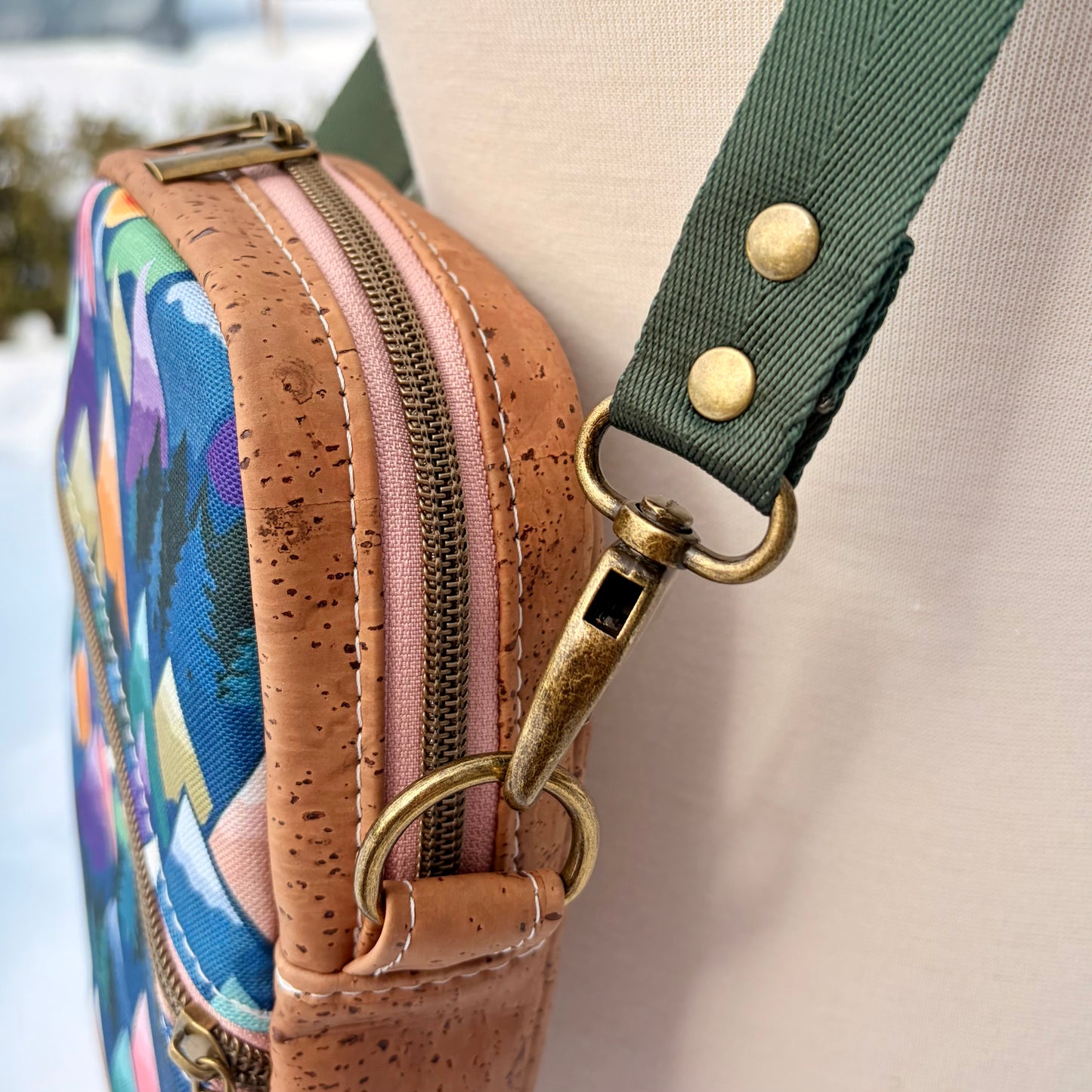 Sac bandoulière en liège brun pâle au devant en canevas à motif montagnes colorées.