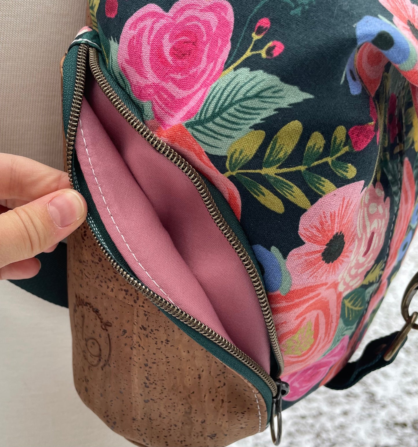 Sac à dos en canvas vert foncé à motifs de fleurs colorées et au liège brun pâle.