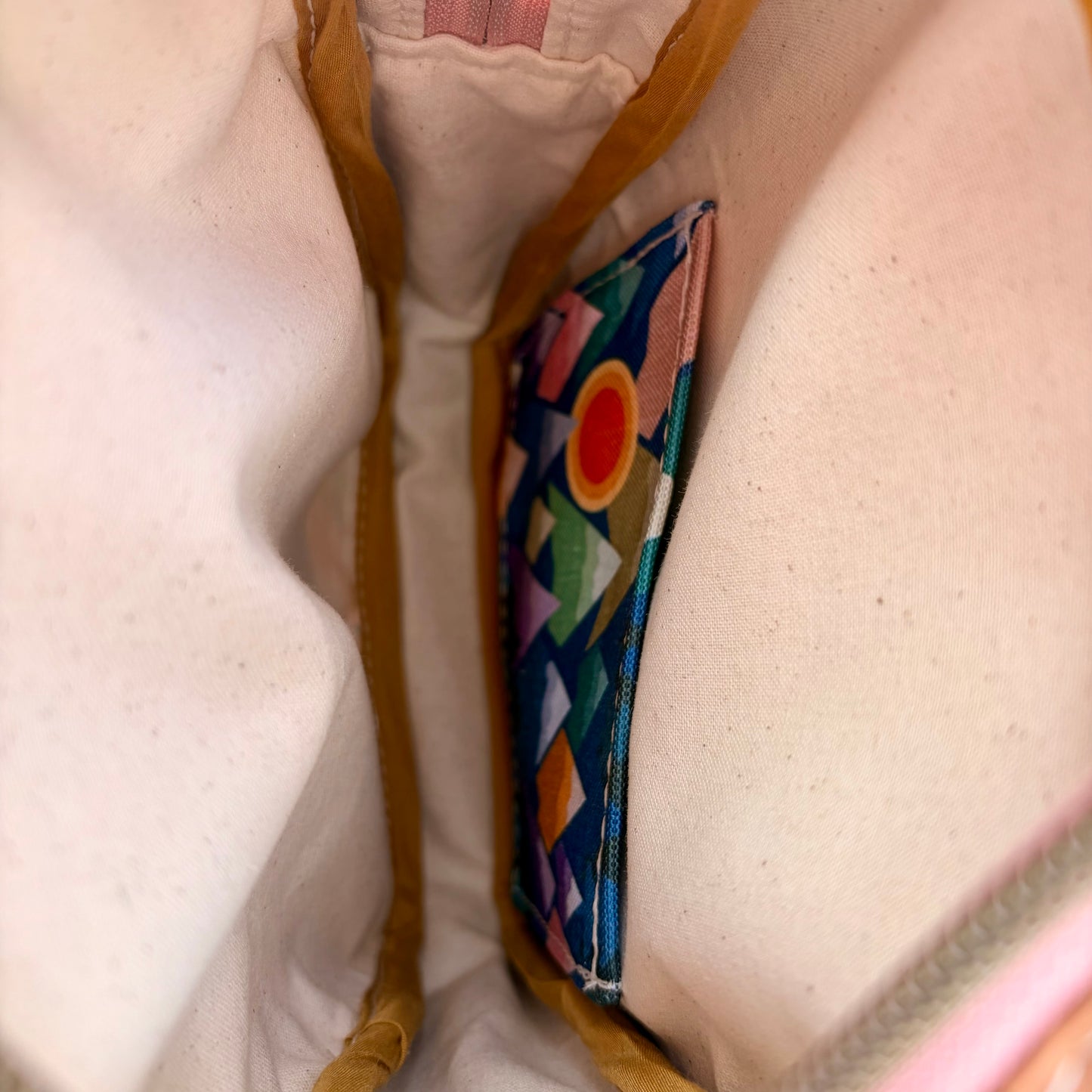 Sac bandoulière en liège brun pâle au devant en canevas à motif montagnes colorées.